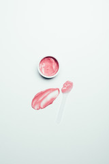 top view of smudge, spoon and pink mask in container on white surface