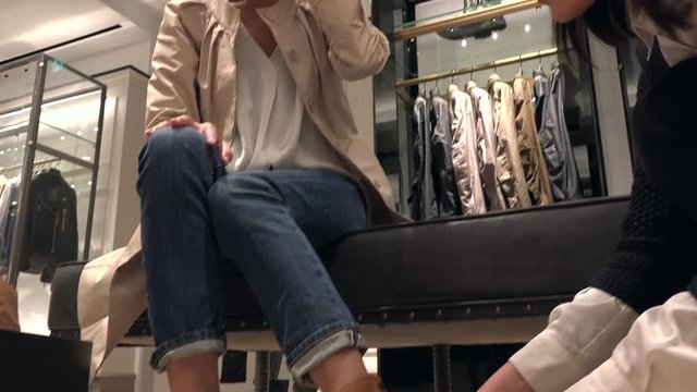 Asian people shopping for fashion goods and accessories. Japanese woman in luxury shop inside mall. Female client buying new shoes in store and speaking to sales manager for advice and assistance