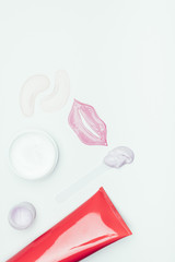 top view of lip mask, eye patches, clay mask in container and cream bottle isolated on white surface