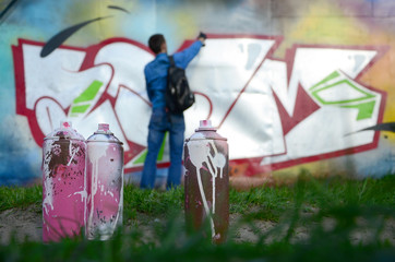 A few used paint cans against the background of the space with the wall on which the young guy...