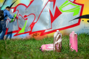 A few used paint cans against the background of the space with the wall on which the young guy...