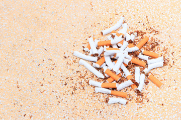 Pile cigarettes broken on table terrazzo flooring yellow background. health care concept stop quitting smoking.