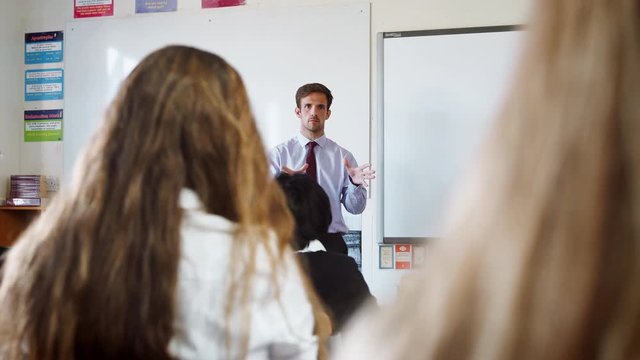 Teenage Students Listening To Male Teacher In Classroom