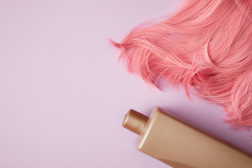 top view of bright pink wig and blank container on purple