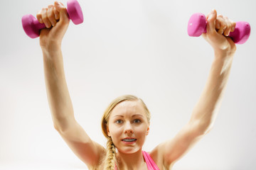 Teenage woman working out at home with dumbbell