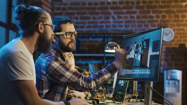 Side view of diverse group of people sitting at table with computer and coworking on creation of new cartoon