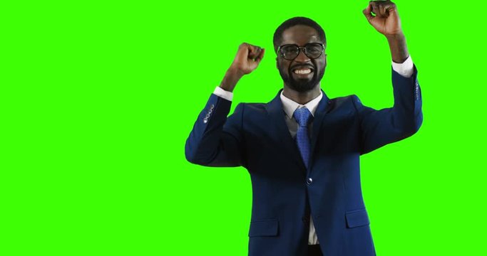 Happy African American young man in glasses being very cheerful and feeling great on the green screen background. Chroma key.