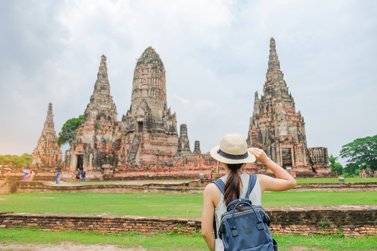 Young Woman traveling backpack with hat, Asian traveler looking to Wat Chaiwatthanaram temple in Ayutthaya Historical Park, a UNESCO world heritage site in Thailand. summer Travel concept