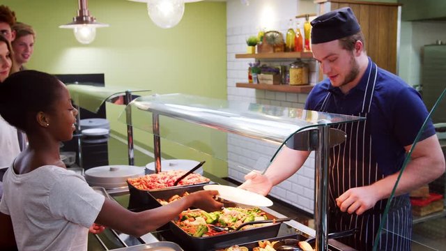 Teenage Students Being Served Meal In School Canteen