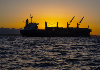 Fototapeta premium Cargo ship Sunset water and mountains 
