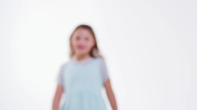 Girl Walks Into Focus And Poses Against White Studio Background 