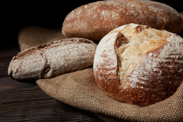 close up image of various types of bread and sackcloth on wooden table
