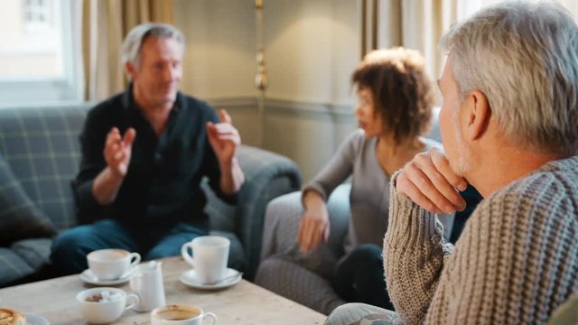 Group Of Middle Aged Friends Meeting Around Table In Coffee Shop