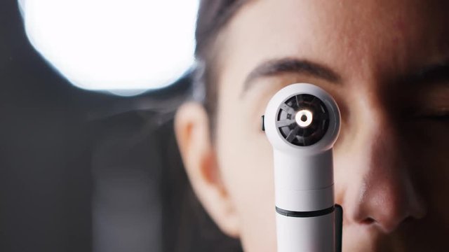 Woman using otoscope for examination, close up, half of face