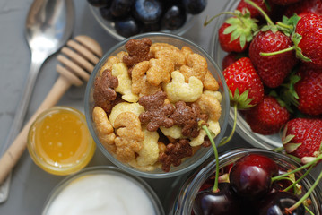 Healthy Breakfast with Oat Flakes, Natural Yogurt, Fresh Blueberries, Strawberries, Almonds and Honey in Glass Bowls. Flat Lay.