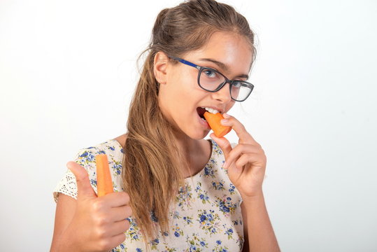 girl with carrot. Vitamins for teenagers. Vegetabl for healthy eating of children. Positive weight loss.  girl with glasses. girl bites a carrot. Natural vitamins 
