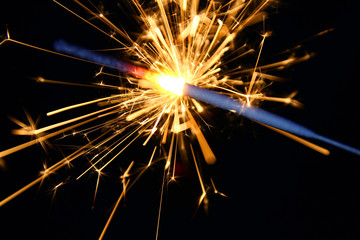 Sparkler background / A sparkler is a type of hand-held firework that burns slowly while emitting colored flames, sparks, and other effects.