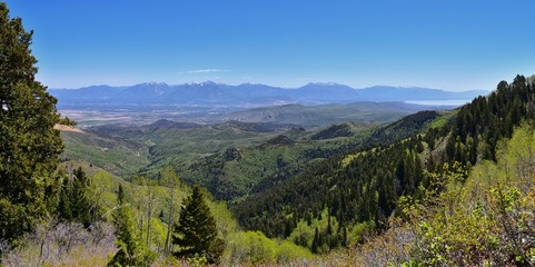 Fototapeta na wymiar Panoramic view of Wasatch Front Rocky Mountains from the Oquirrh Mountains, by Kennecott Rio Tinto Copper mine, Utah Lake and Great Salt Lake Valley in early spring with melting snow and Cloudscape. U
