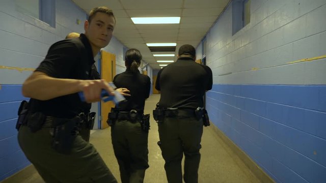 A squad of police walk in a school with guns drawn to train for responding to school shootings.