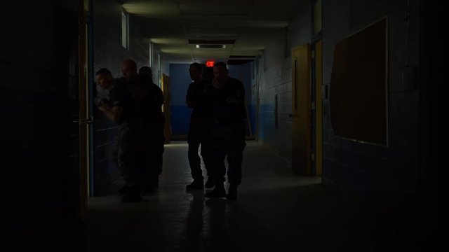 A squad of SWAT team police walk in a school with guns drawn to train for responding to school shootings.