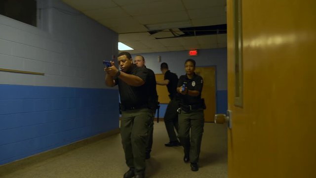 A squad of police walk in a school with guns drawn to train for responding to school shootings.