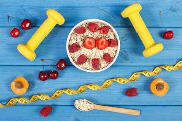 Oat flakes with fruits, dumbbells and centimeter, concept of slimming and healthy lifestyle