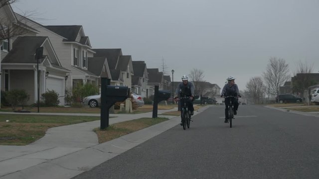 Two police officers patrol a neighborhood on bicycles to look for crimes and do law enforcement.