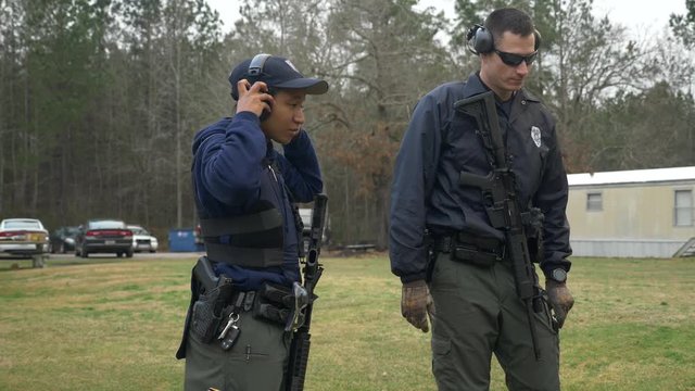 A female police officer puts on hearing protection before shooting her gun at a firing range for target practice.