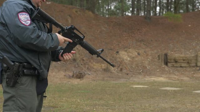 Police officer reloads his assault rifle during target practice at a gun range.