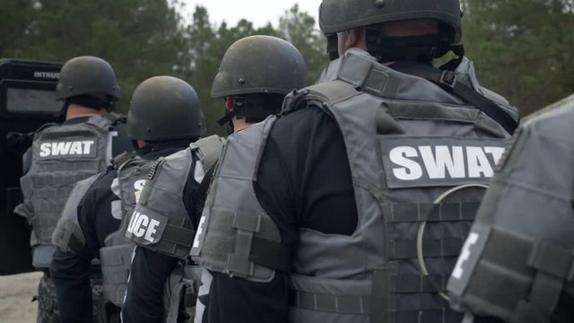 A SWAT police team prepares to make a combat assault in counterterrorism training with a riot shield and handgun.