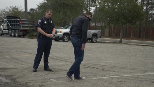 A drunk person tries to pass a DUI test during a traffic stop with a police officer.