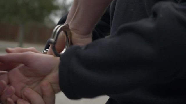Police officer handcuffs a drunk driver who failed a DUI test during a traffic stop.