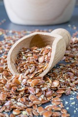 A close up image of a wooden scoop full of linseed.