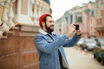 Handsome trendy hipster taking photography outdoors