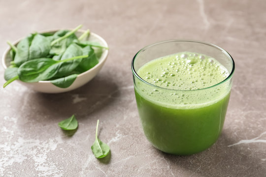 Glass with delicious detox juice and spinach on table