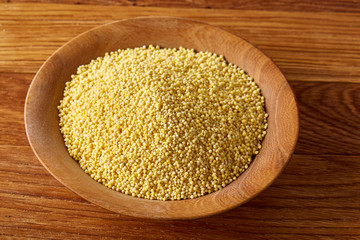 A wooden dish with millet on rustic wooden background, top view, close-up, selective focus.