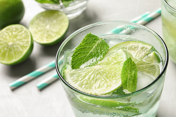 Refreshing beverage with mint and lime in glass on table, closeup