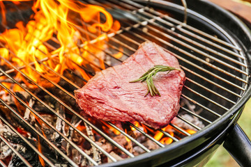 Tasty meat on barbecue grill with fire flames outdoors, closeup