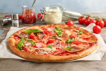 Delicious pizza with tomatoes and meat on table