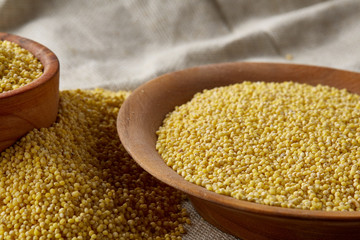Two bowls of millet on a wooden background, top view, close-up, selective focus.