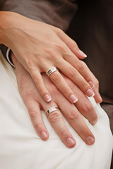 The bride and groom hold hands together with rings
