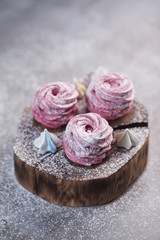 Homemade pink swirled meringue cookies on a dark wooden board