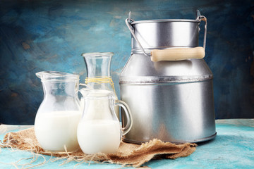 A jug of milk and glass of milk on a wooden table