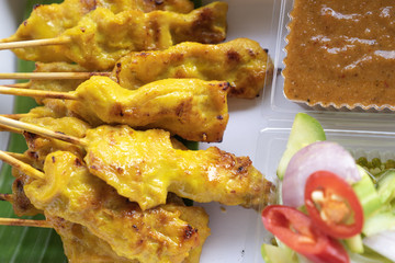 close up pork satay skewers with peanut dipping suace and sider in white paper box one of famous...