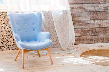Fototapeta na wymiar Comfortable soft armchair in scandinavian eco loft apartment. Modern minimalist living room with woodpile.