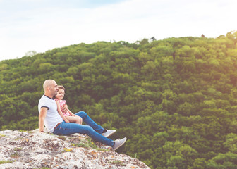 Father and daughter sitting on the mountain rock