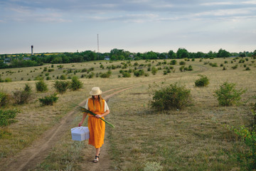 A woman in a straw hat and a gift box walks