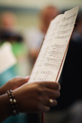 A woman sings in a choir and holds her sheet music notes