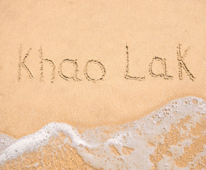 The word Khao Lak written in the sand on beach