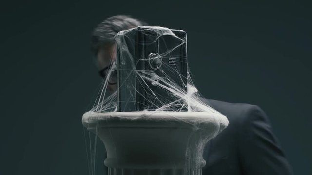 Businessman and dusty safe with cobwebs